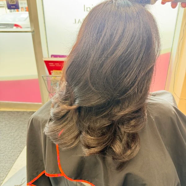 Brown hair with warm highlights and layered curled ends
