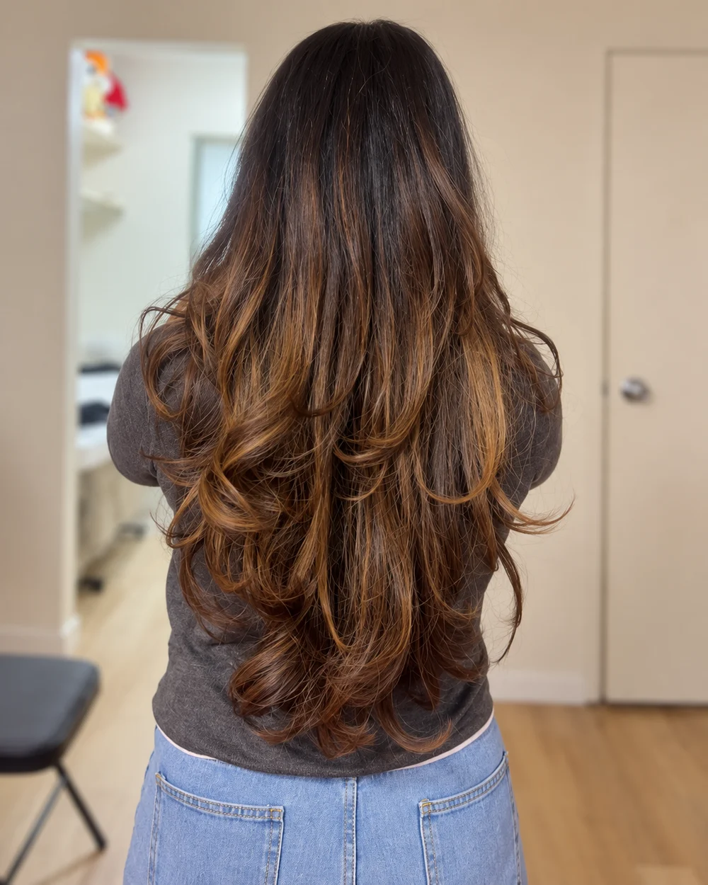Long brown layered hair with softly curled ends, viewed from behind