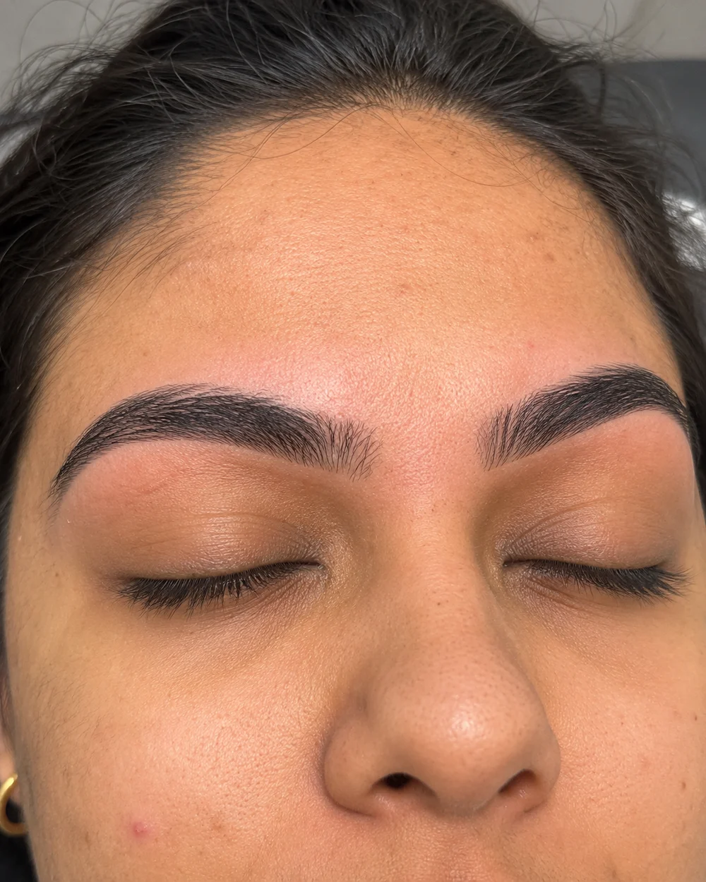 Close-up of shaped eyebrows and closed eyes with natural skin texture