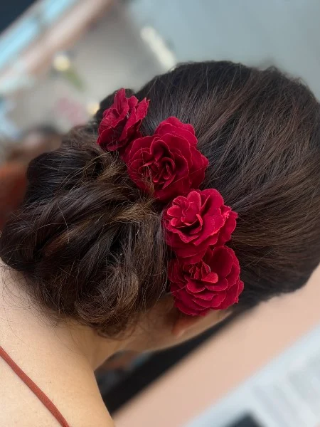 Low braided bun decorated with deep red roses
