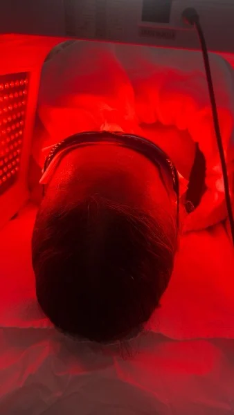 Client resting beneath a red-light skin-care device